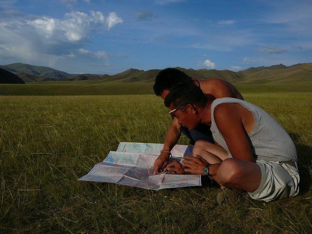 Patso y Tse con los que Ernesto Díaz viajó al Gobi, consultando un mapa.
